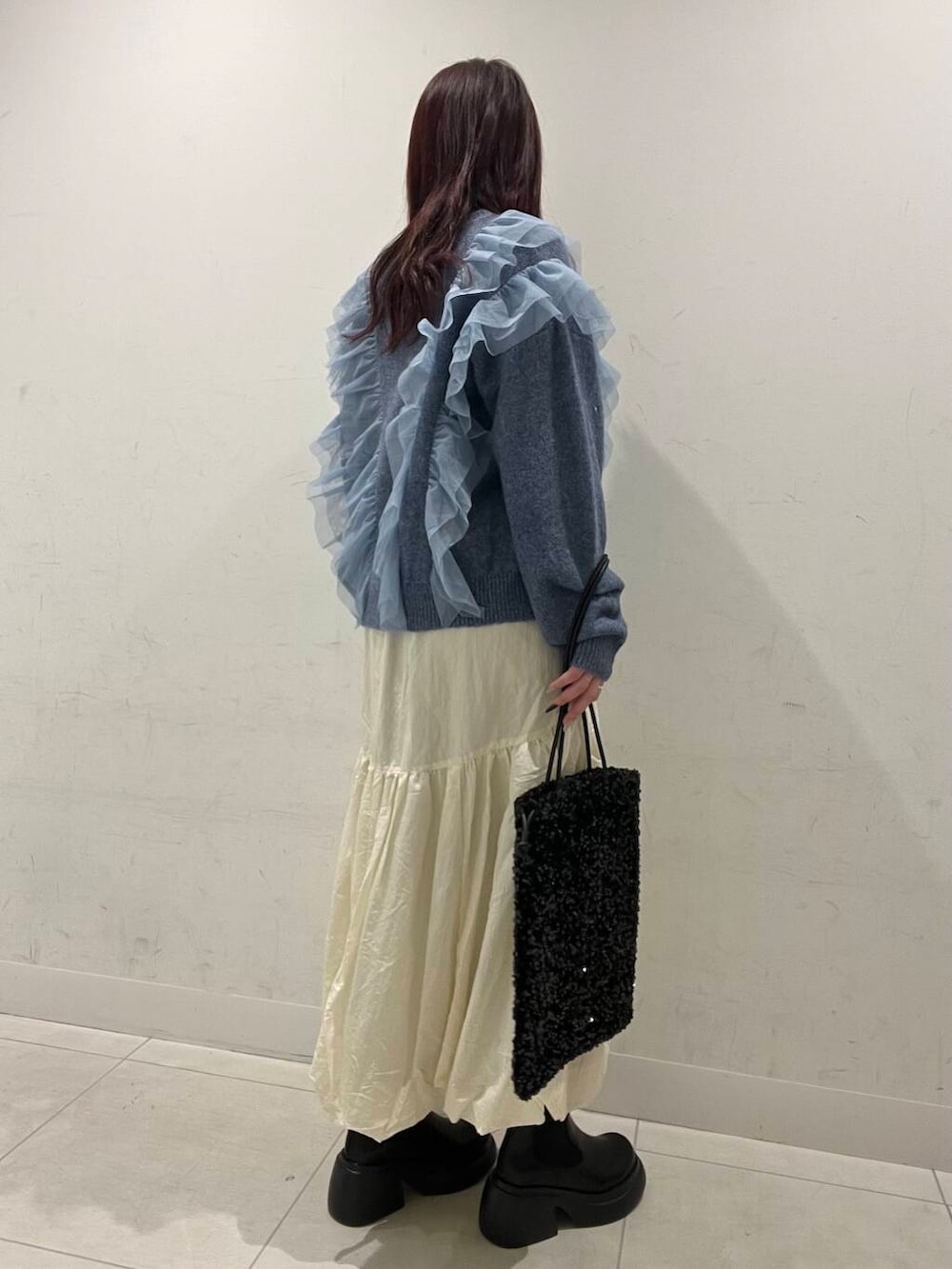 ブラック系のブーツ、ホワイト系のスカート、ブラック系のトートバッグを着用したレディースの冬コーディネートの2枚目の写真