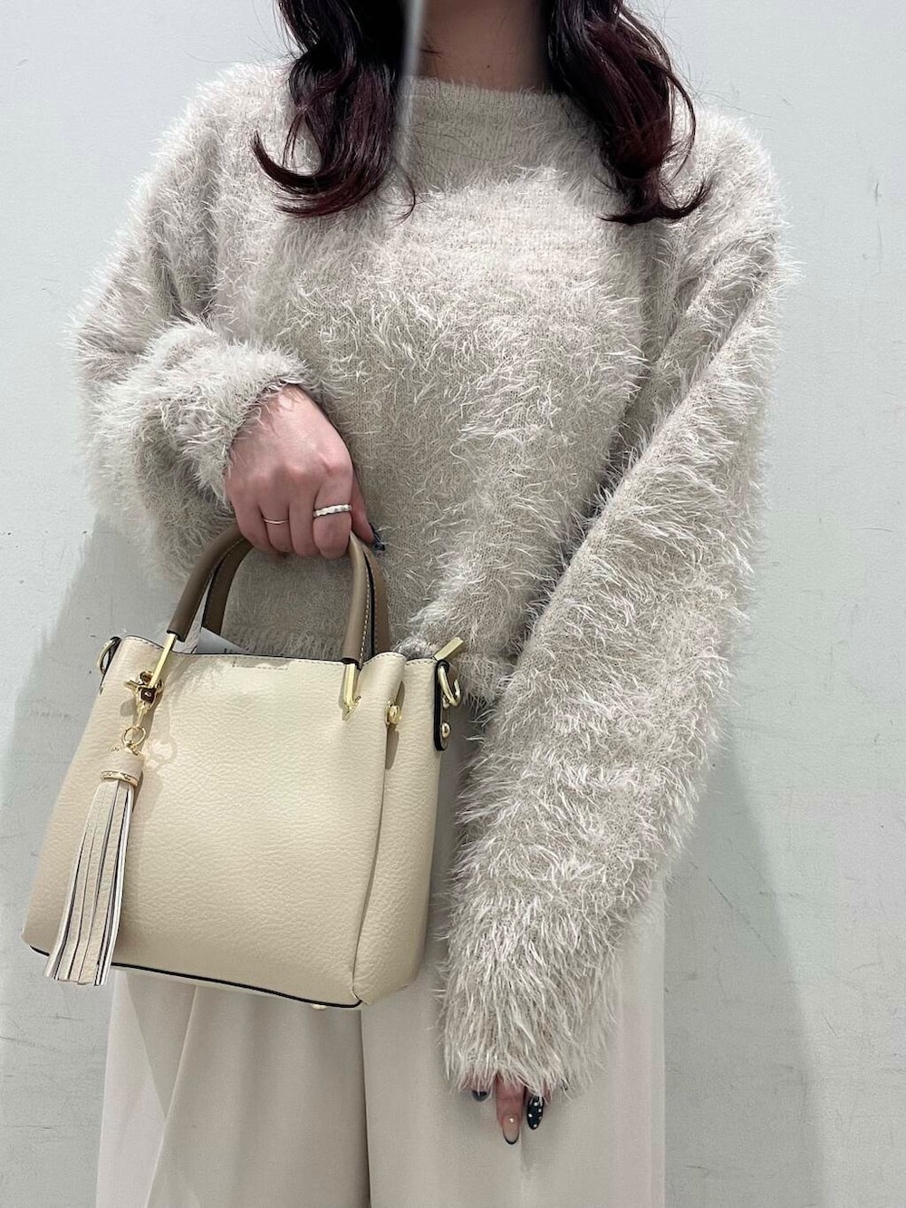 ホワイト系のトートバッグ、ブラック系のブーツ、ベージュ系のニット/セーターを着用したレディースの冬コーディネートの3枚目の写真