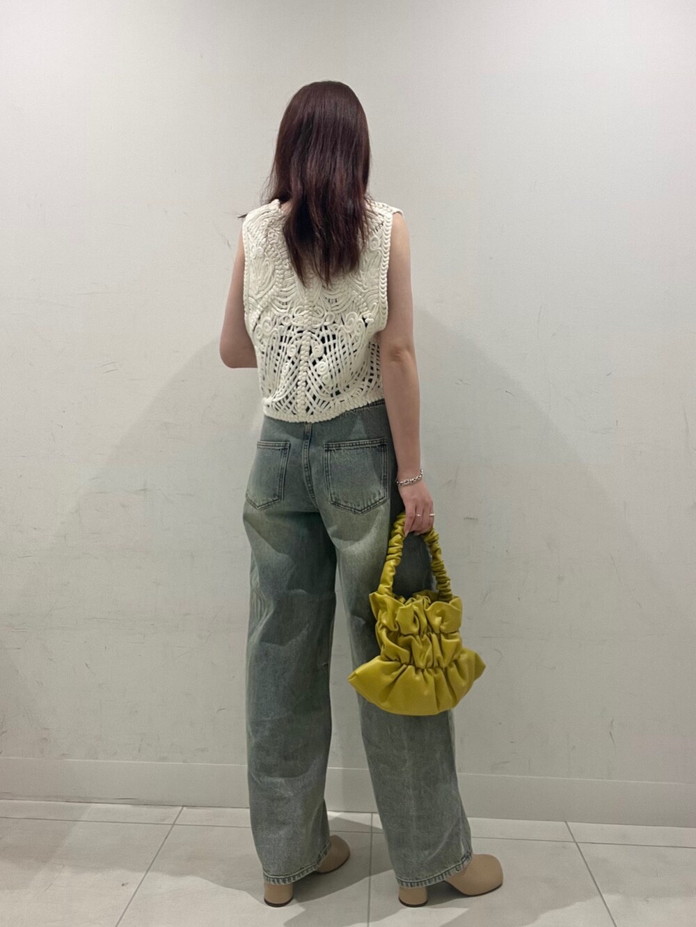 ホワイト系のベスト、ブラウン系のキャミソール、ベージュ系のサンダルを着用したレディースの秋コーディネートの2枚目の写真