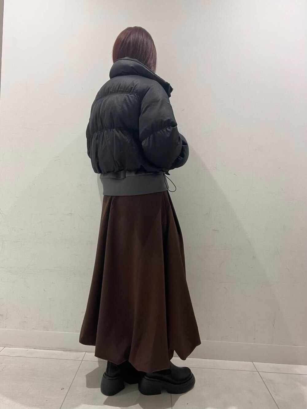 ベージュ系のハンドバッグ、ブラック系のダウンジャケット/コート、ブラック系のブーツを着用したレディースの冬コーディネートの3枚目の写真