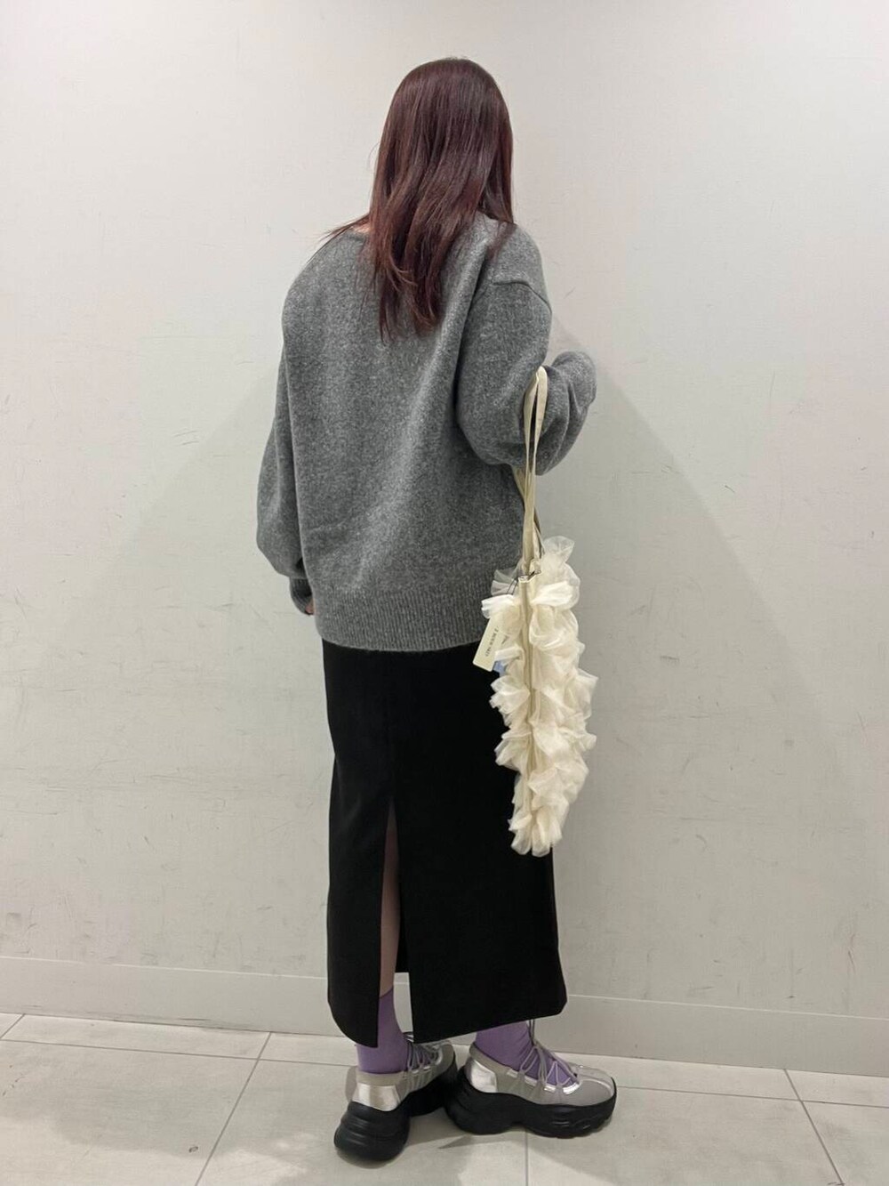 ホワイト系のトートバッグ、グレー系のスニーカー、グレー系のスカートを着用したレディースの冬コーディネートの2枚目の写真