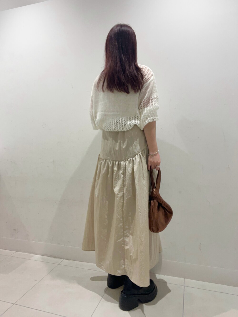 ベージュ系のスカート、ブラック系のブーツ、ホワイト系のニット/セーターを着用したレディースの秋コーディネートの2枚目の写真