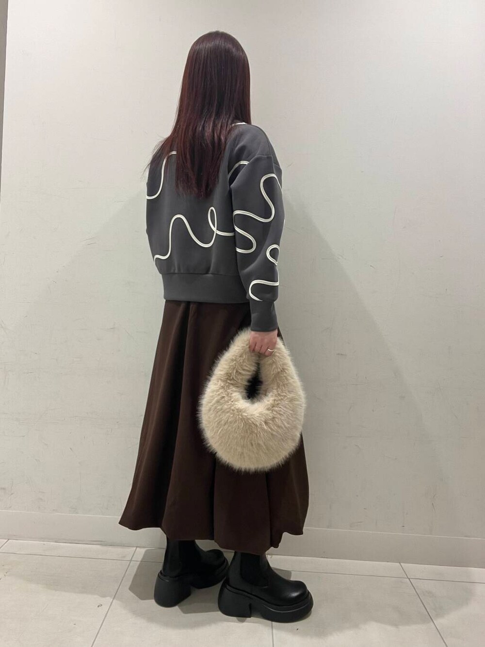 ベージュ系のハンドバッグ、ブラック系のダウンジャケット/コート、ブラック系のブーツを着用したレディースの冬コーディネートの2枚目の写真