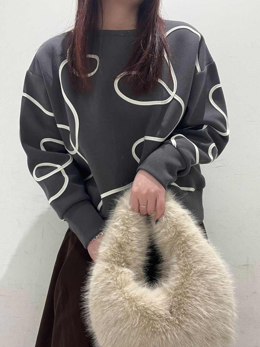 ベージュ系のハンドバッグ、ブラック系のダウンジャケット/コート、ブラック系のブーツを着用したレディースの冬コーディネートの4枚目の写真