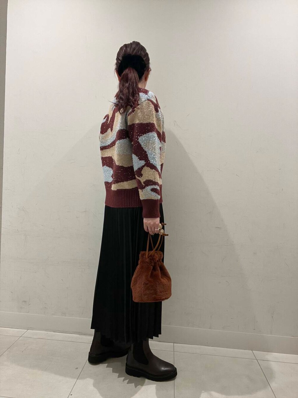 ピンク系のニット/セーター、ブラウン系のブーツ、ブラウン系のショルダーバッグを着用したレディースの冬コーディネートの2枚目の写真