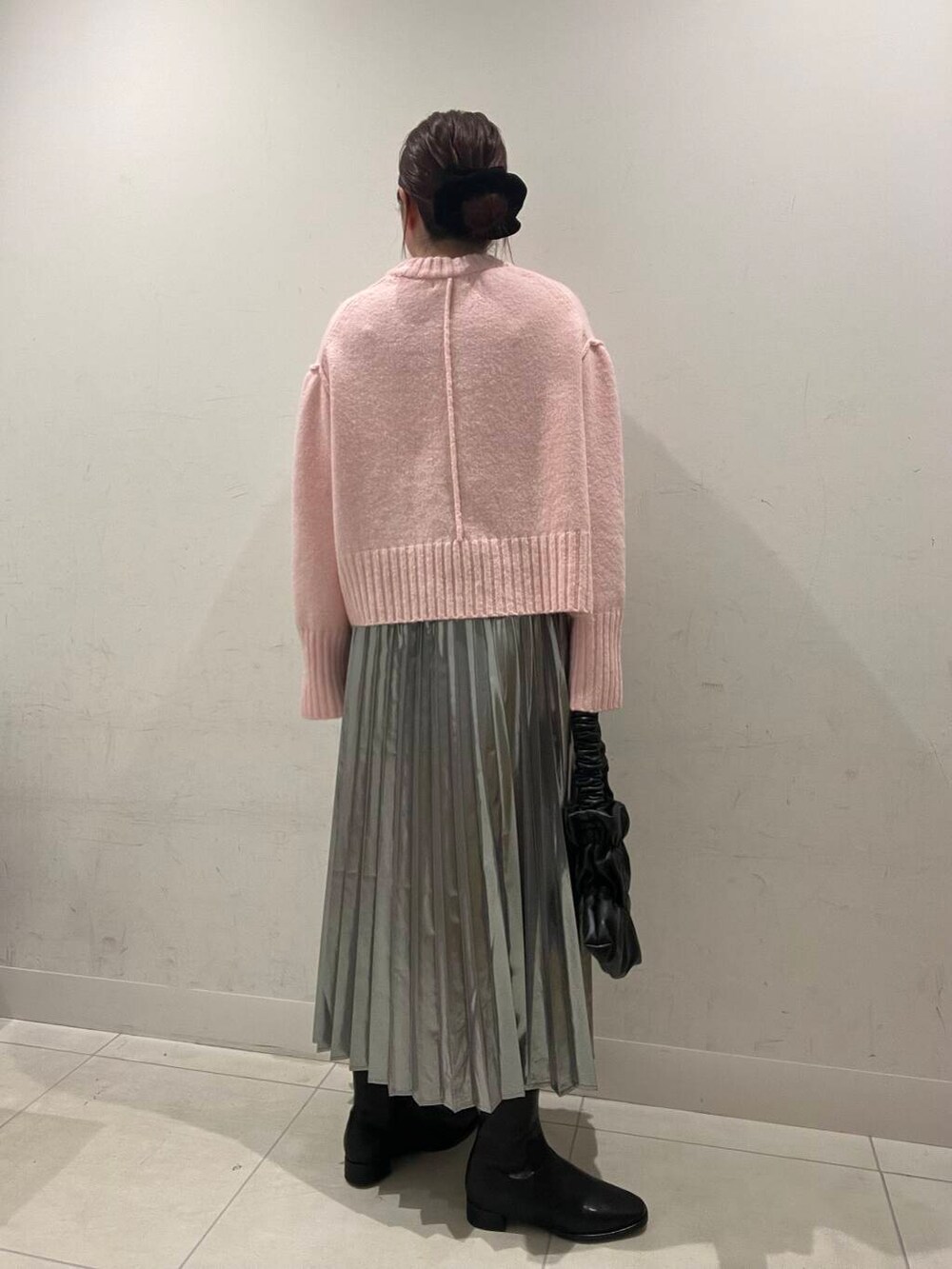 ブラック系のハンドバッグ、ブラック系のブーツ、シルバー系のスカートを着用したレディースの冬コーディネートの2枚目の写真