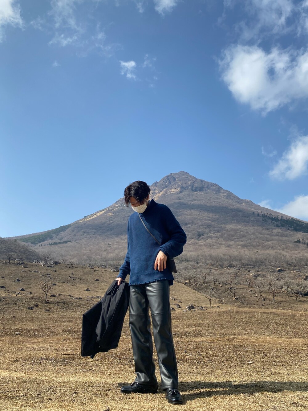 ブラック系のトレンチコート、ブルー系のニット/セーター、ブラック系のその他パンツを着用したメンズの春コーディネートの2枚目の写真