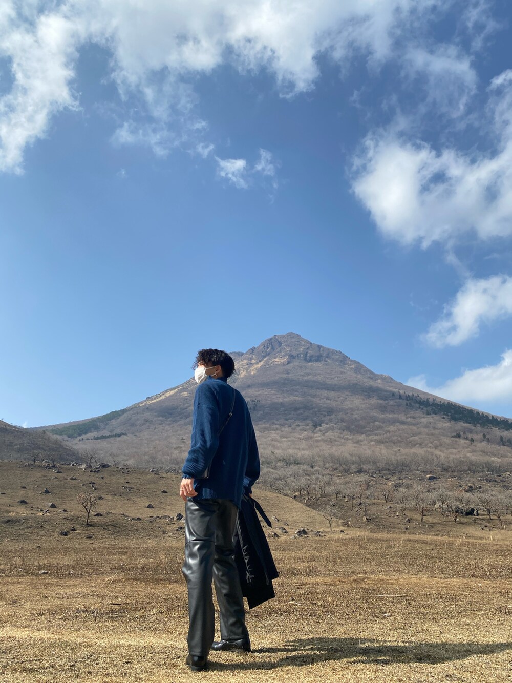 ブラック系のトレンチコート、ブルー系のニット/セーター、ブラック系のその他パンツを着用したメンズの春コーディネートの3枚目の写真