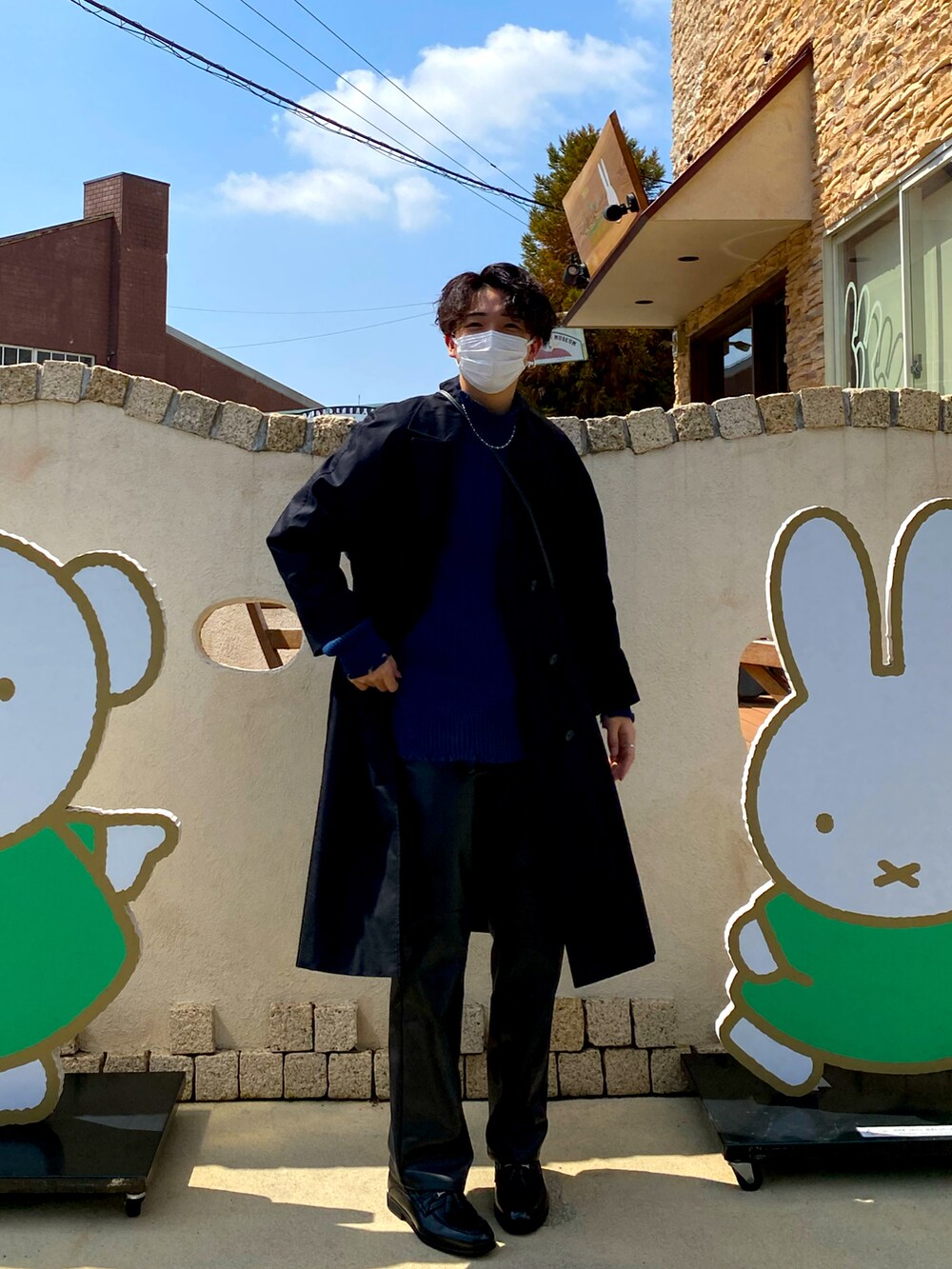 ブラック系のトレンチコート、ブルー系のトップス、ブラック系のパンツを着用したメンズの春コーディネートの2枚目の写真