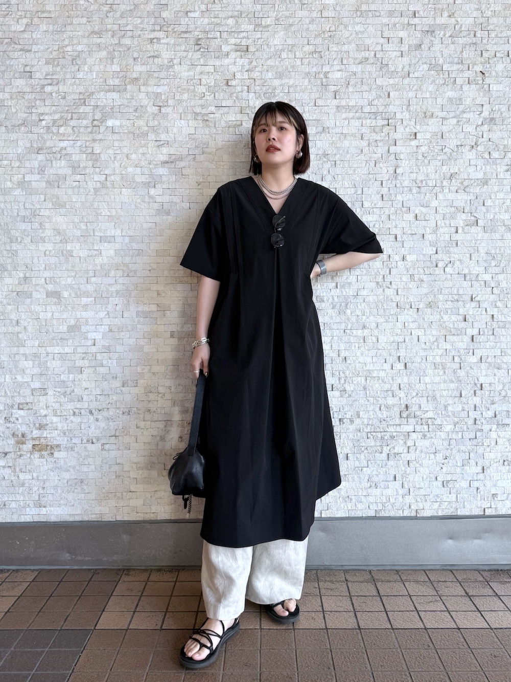 ブラック系のワンピース、ブラック系のショルダーバッグ、シルバー系のネックレスを着用したレディースの春コーディネートの2枚目の写真