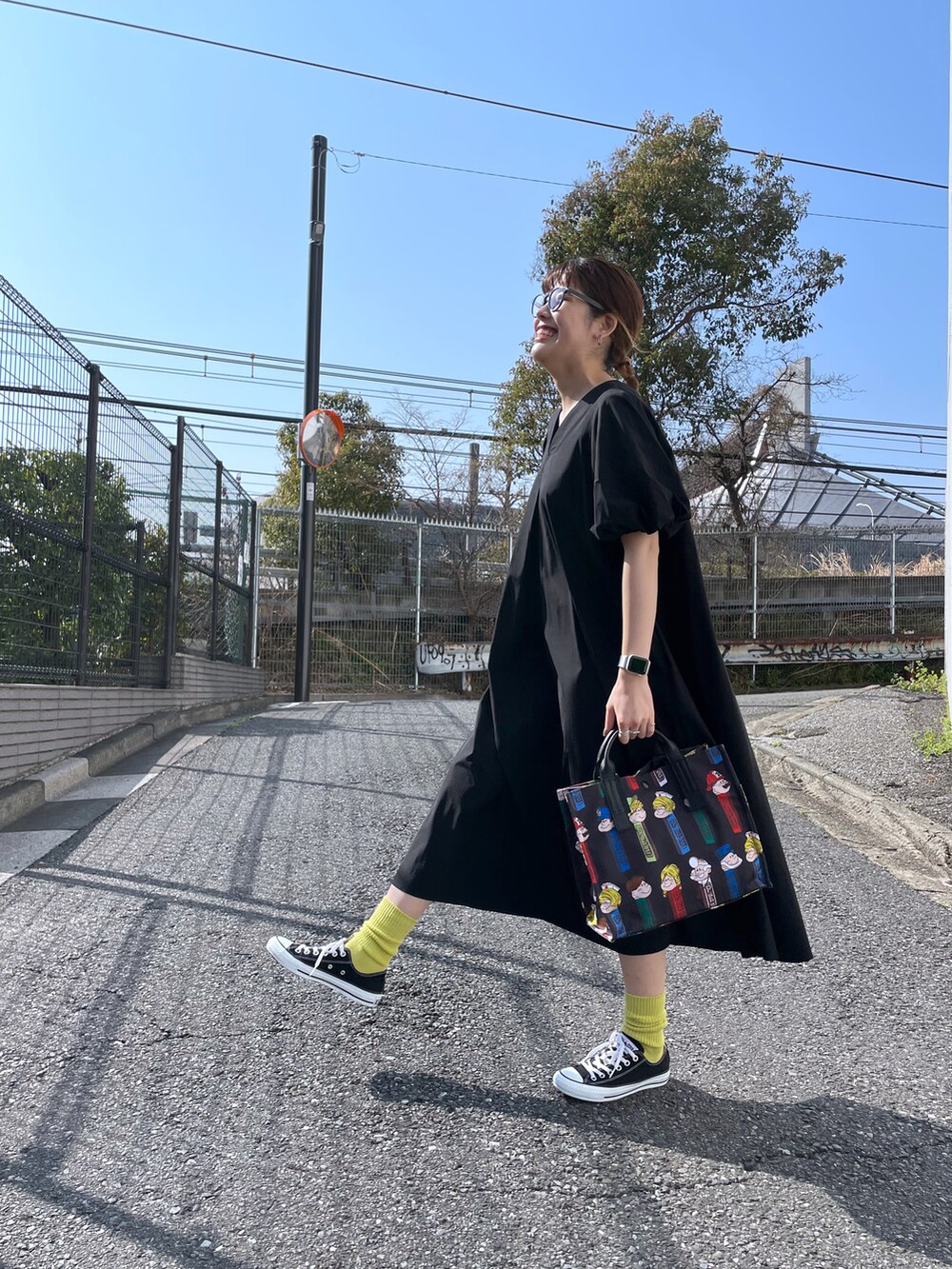 ブラック系のトートバッグ、ブラック系のワンピース、ブラック系のスニーカーを着用したレディースの春コーディネートの2枚目の写真