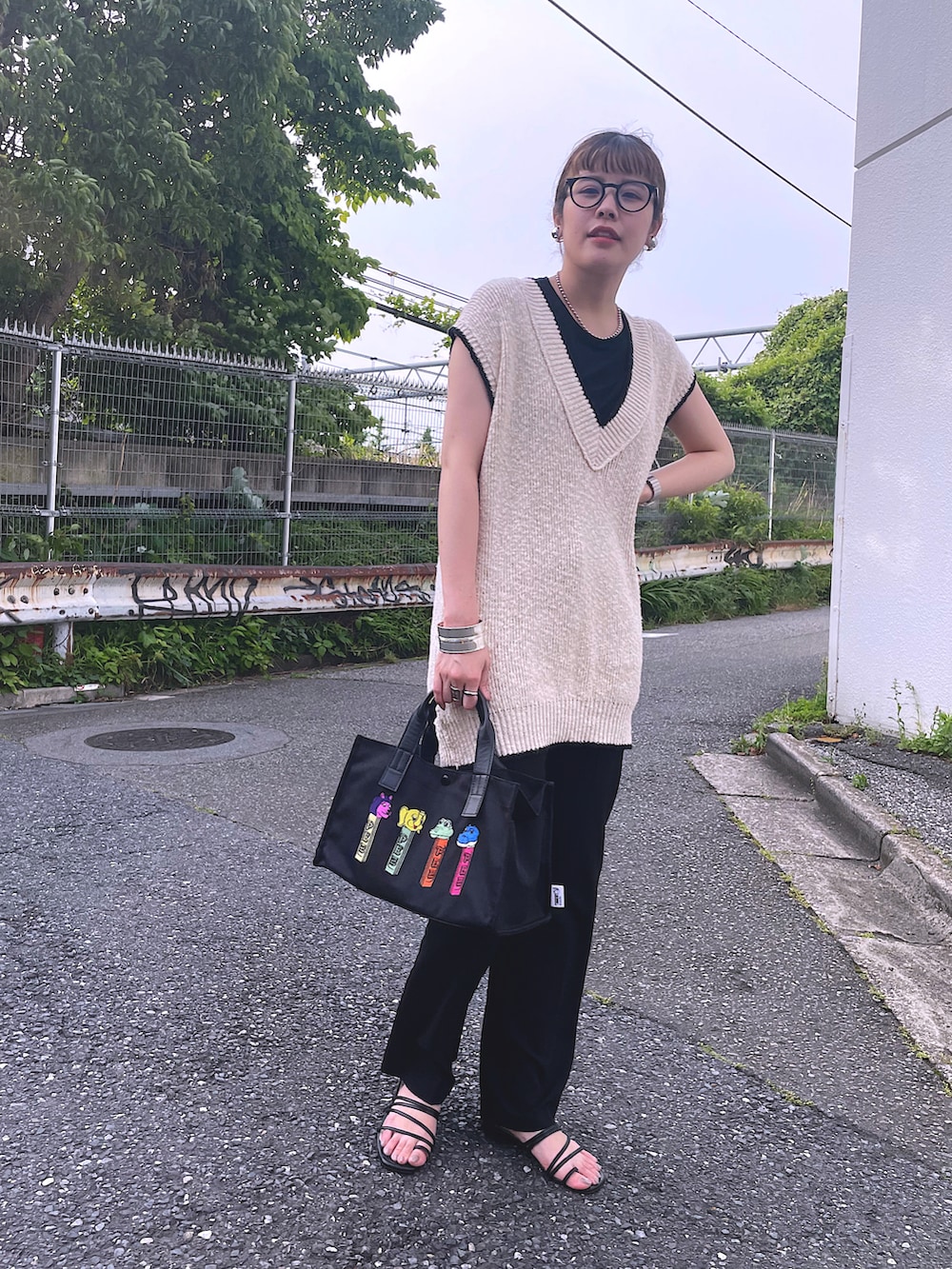 ブラック系のトートバッグ、ホワイト系のベストを着用したレディースの春コーディネートの2枚目の写真