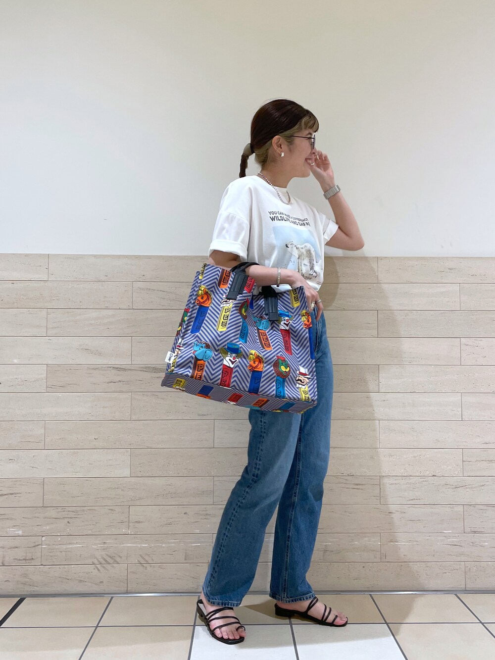 ホワイト系のTシャツ/カットソー、ブルー系のトートバッグ、ブルー系のパンツを着用したレディースの夏コーディネートの2枚目の写真