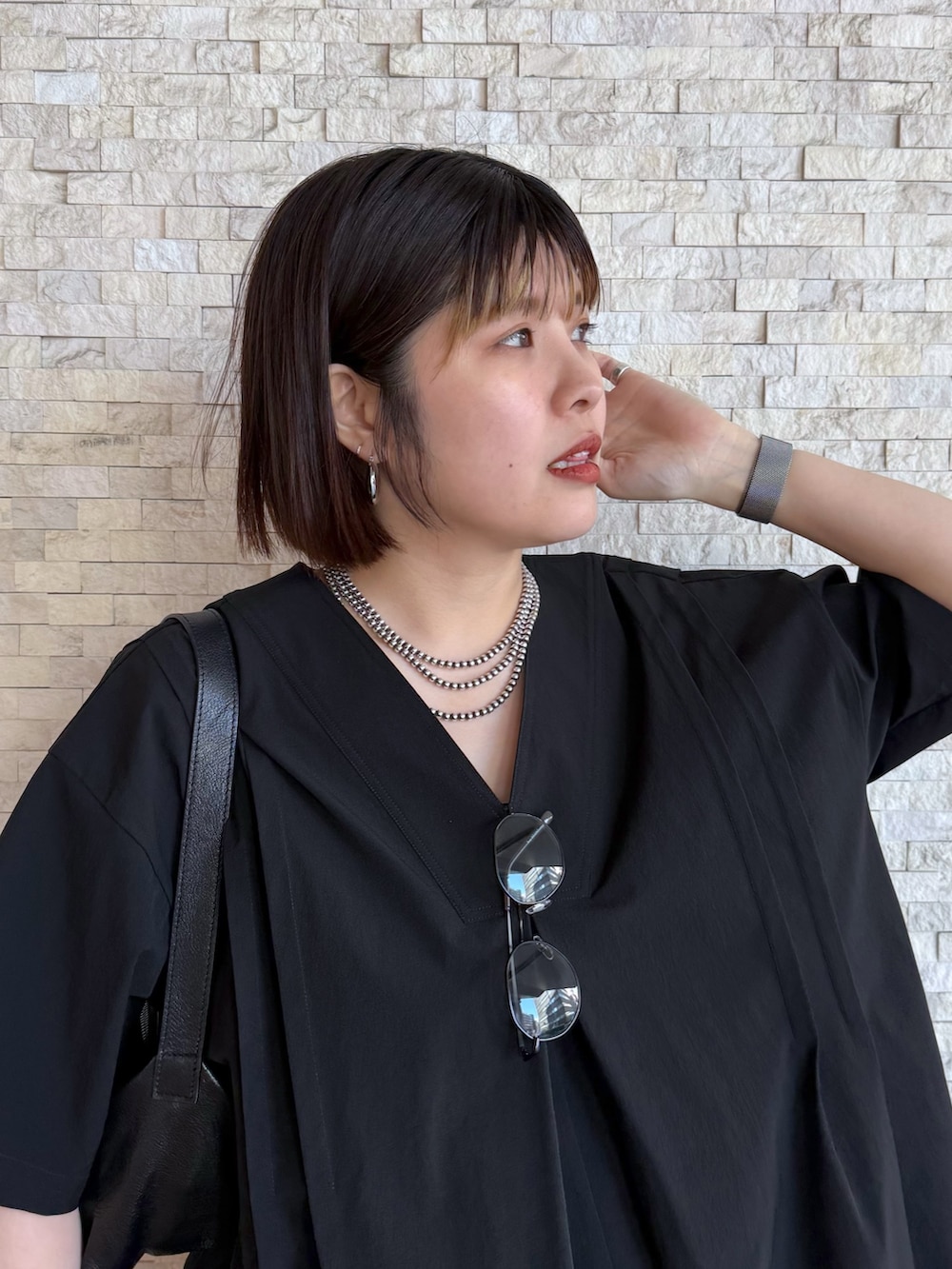 ブラック系のワンピース、ブラック系のショルダーバッグ、シルバー系のネックレスを着用したレディースの春コーディネートの4枚目の写真