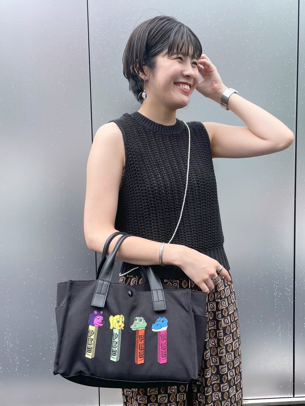 ブラック系のトートバッグ、ブラック系のニット/セーター、ブラック系のサンダルを着用したレディースの夏コーディネートの2枚目の写真