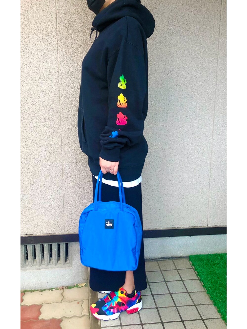 ブラック系のパーカー、ブラック系のスカート、ブルー系のハンドバッグを着用したレディースの春コーディネートの2枚目の写真