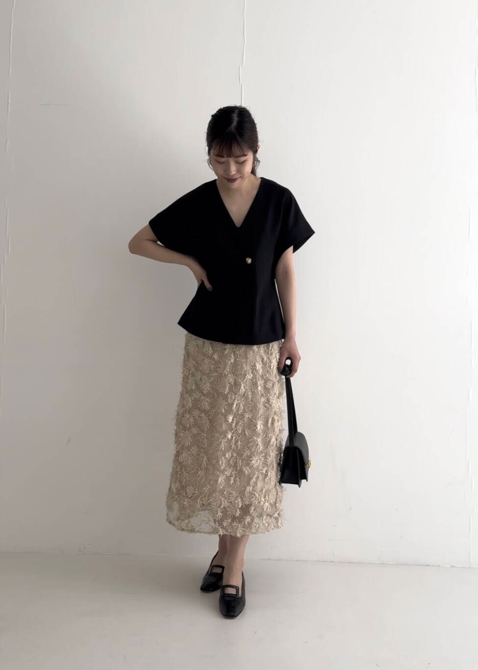 ブラック系のベスト、ベージュ系のスカート、ブラック系のショルダーバッグを着用したレディースの夏コーディネートの4枚目の写真