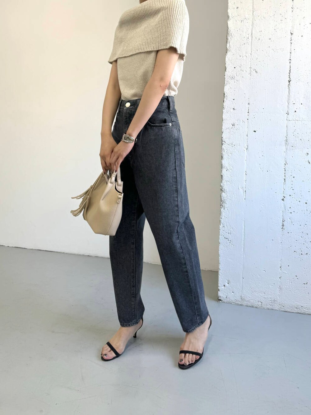 ベージュ系のニット/セーター、グレー系のデニムパンツを着用したレディースの夏コーディネートの6枚目の写真