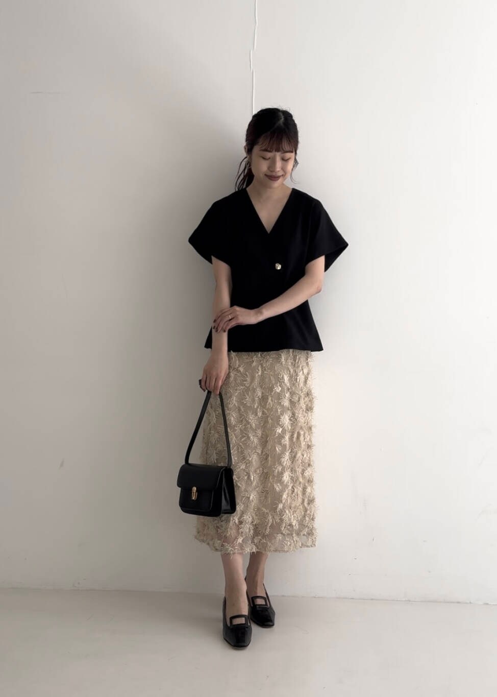 ブラック系のベスト、ベージュ系のスカート、ブラック系のショルダーバッグを着用したレディースの夏コーディネートの3枚目の写真