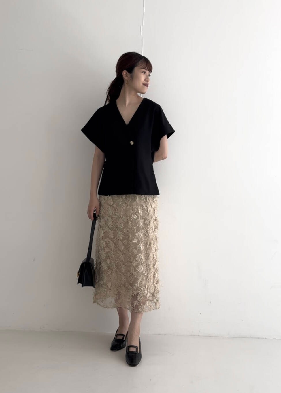 ブラック系のベスト、ベージュ系のスカート、ブラック系のショルダーバッグを着用したレディースの夏コーディネートの2枚目の写真
