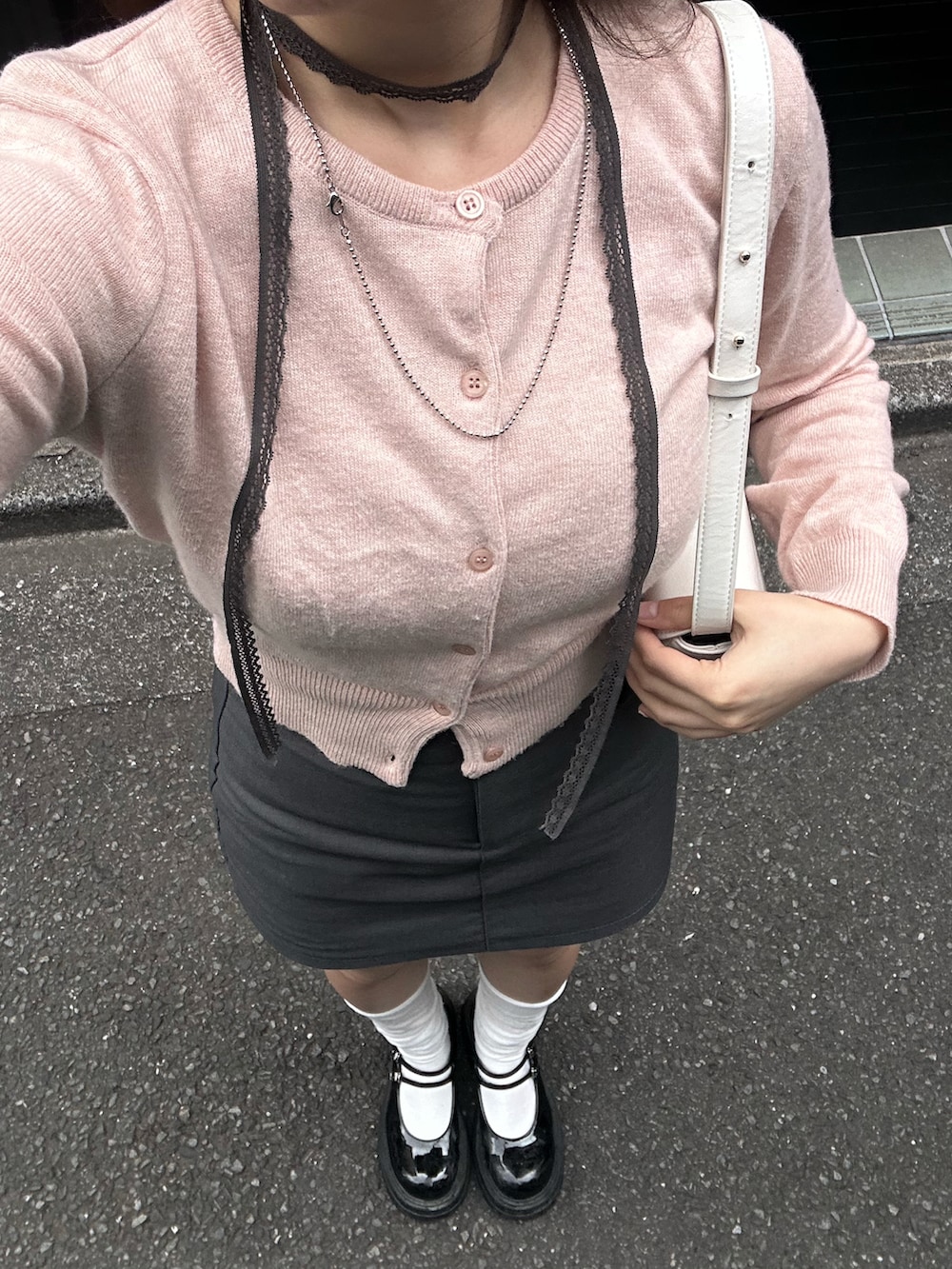 グレー系のスカート、ブラック系のパンプス、ピンク系のカーディガン/ボレロを着用したレディースの春コーディネートの3枚目の写真