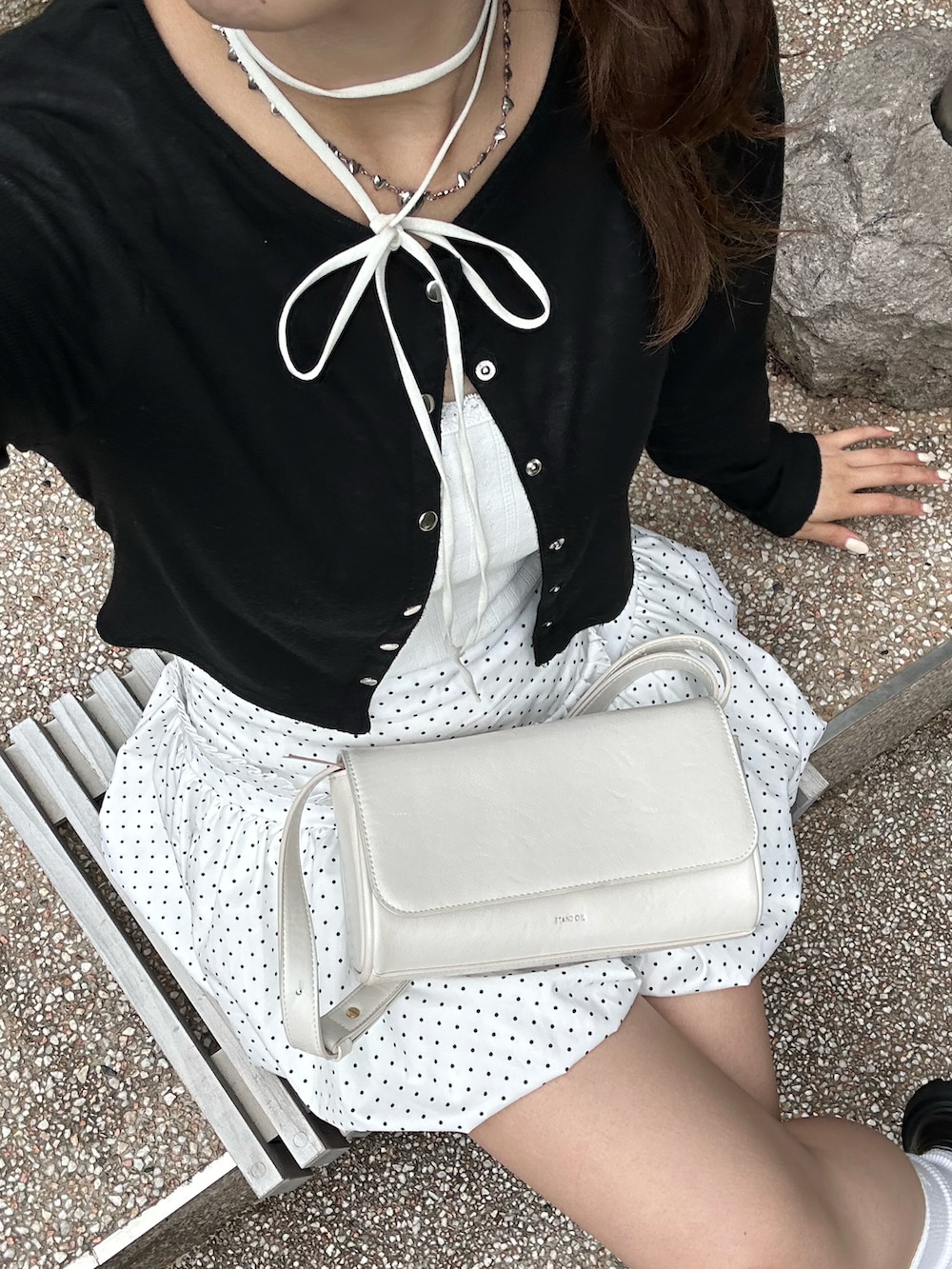 ブラック系のカーディガン/ボレロ、ホワイト系のスカート、ホワイト系のショルダーバッグを着用したレディースの夏コーディネートの2枚目の写真