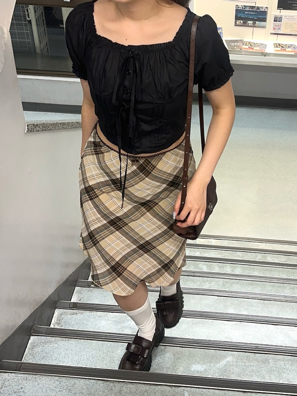 ブラック系のシャツ/ブラウス、ブラウン系のスカート、ブラウン系のローファーを着用したレディースの夏コーディネートの2枚目の写真