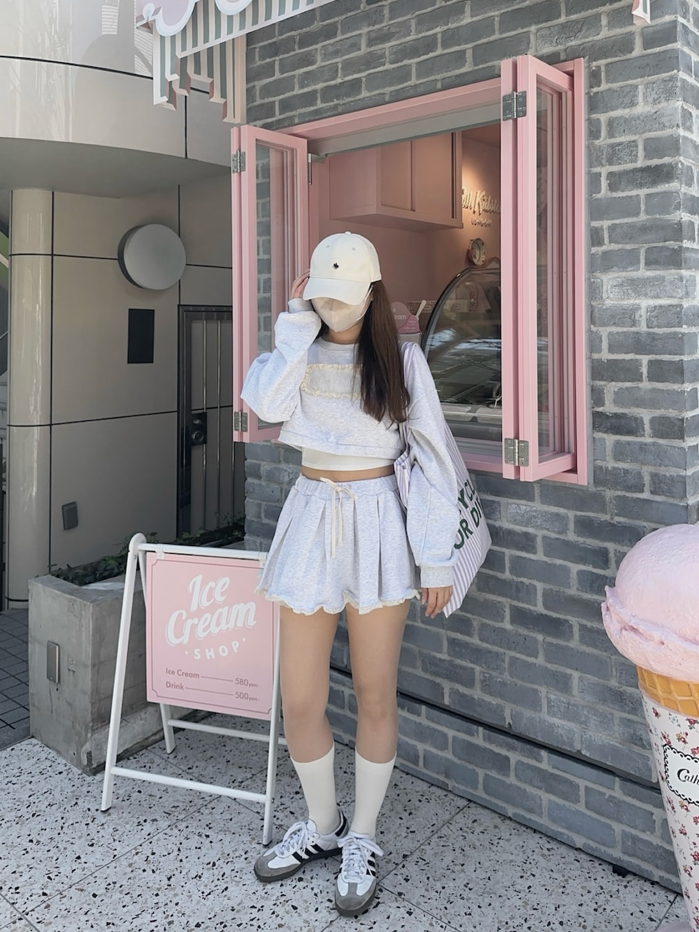 グレー系のスウェット、グレー系のスカート、ホワイト系のスニーカーを着用したレディースの春コーディネートの2枚目の写真