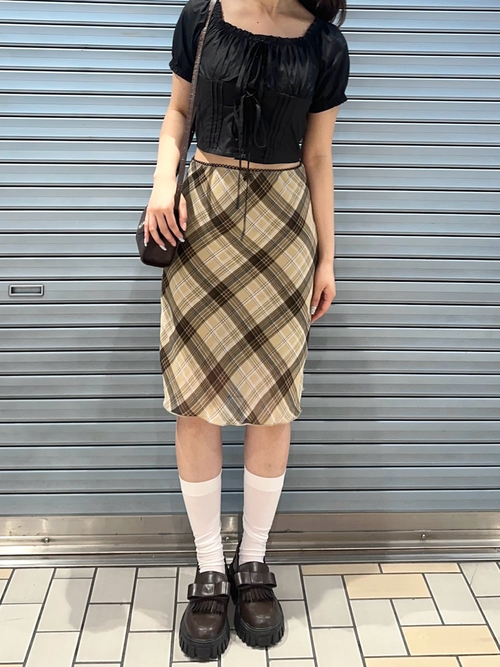 ブラック系のシャツ/ブラウス、ブラウン系のスカート、ブラウン系のローファーを着用したレディースの夏コーディネートの3枚目の写真