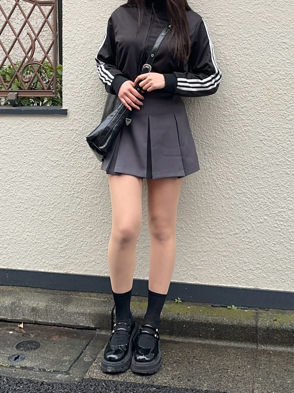 グレー系のスカート、ブラック系のジャージ、ブラック系のショルダーバッグを着用したレディースの冬コーディネートの2枚目の写真