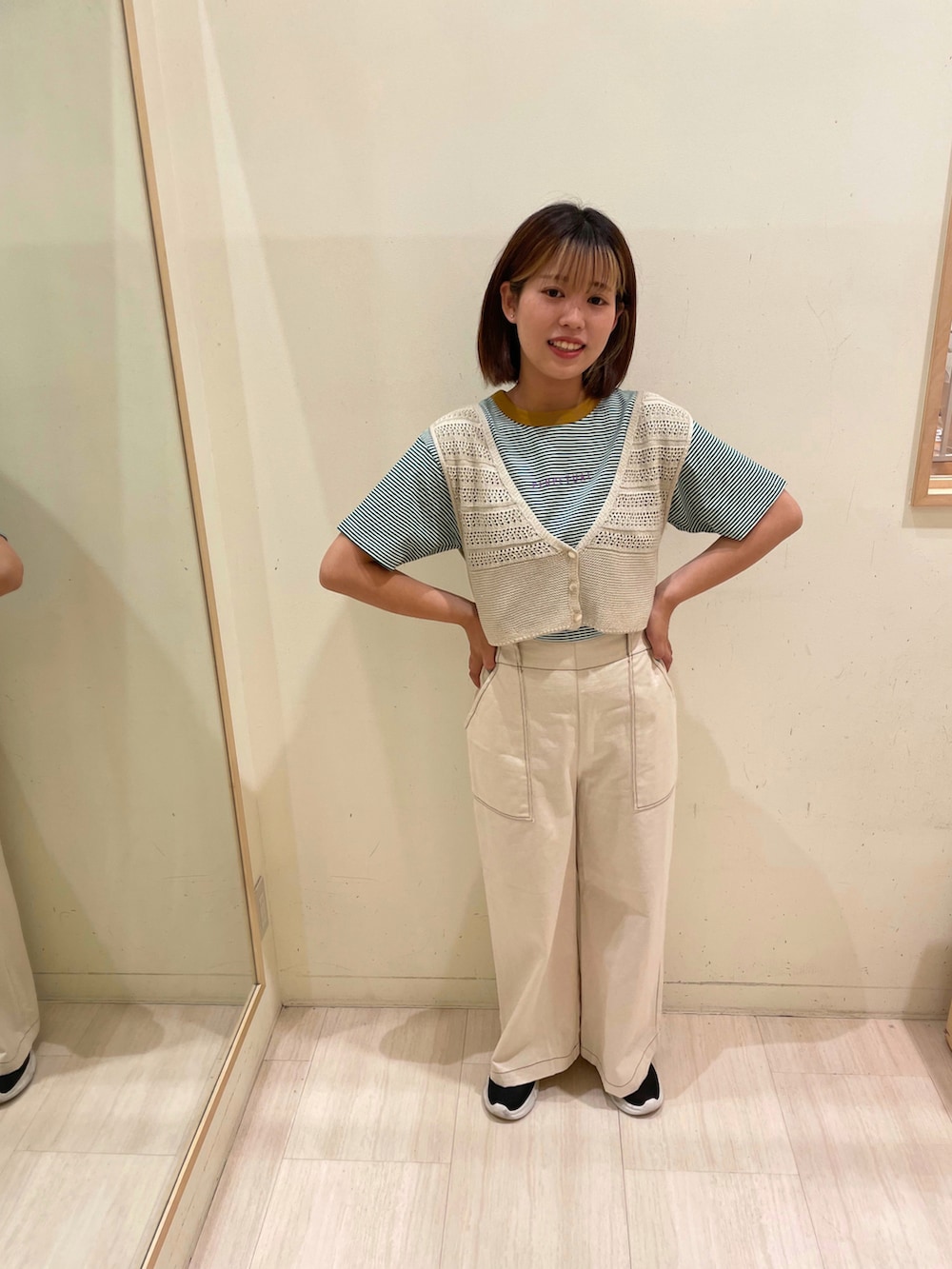 ブラック系のスカート、グリーン系のTシャツ/カットソー、イエロー系のベストを着用したレディースの夏コーディネートの2枚目の写真