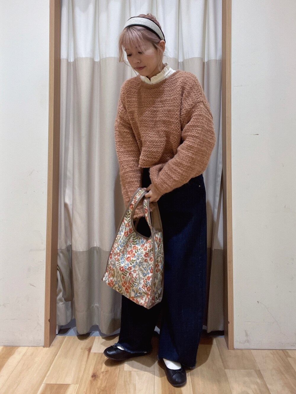 ベージュ系のハンドバッグ、ブルー系のデニムパンツ、オレンジ系のニット/セーターを着用したレディースの秋コーディネートの2枚目の写真