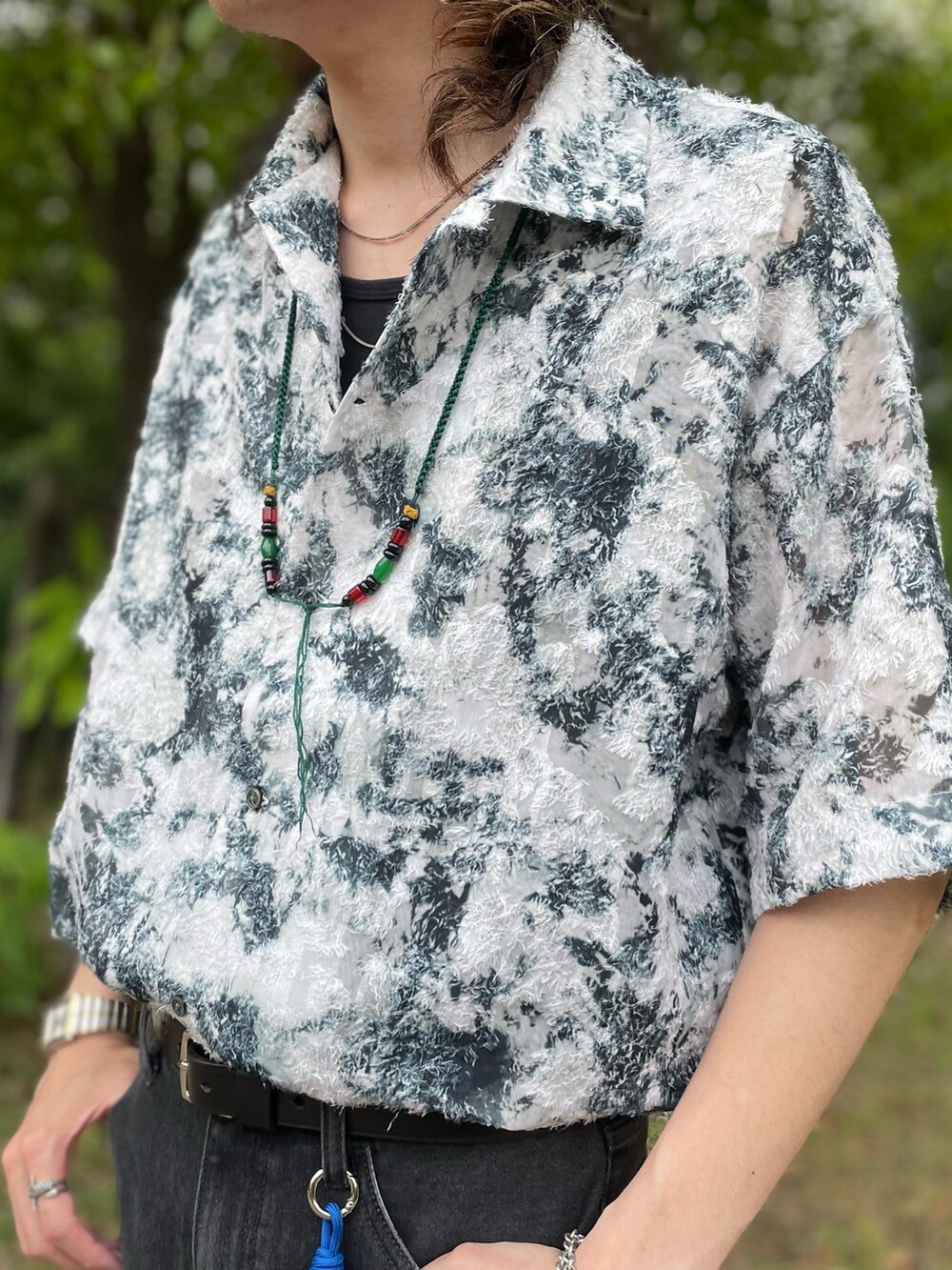 グリーン系のシャツ/ブラウス、ブラック系のタンクトップ、グレー系のデニムパンツを着用したメンズの春コーディネートの2枚目の写真