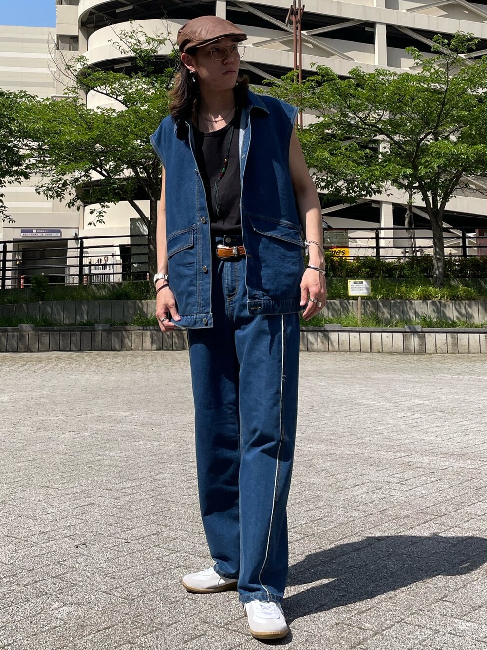 ブルー系のベスト、ブラック系のタンクトップ、ブルー系のデニムパンツを着用したメンズの春コーディネートの2枚目の写真