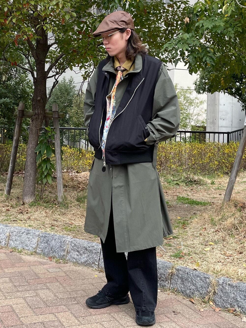 ブラック系のベスト、グリーン系のモッズコート、イエロー系のシャツ/ブラウスを着用したメンズの春コーディネートの2枚目の写真