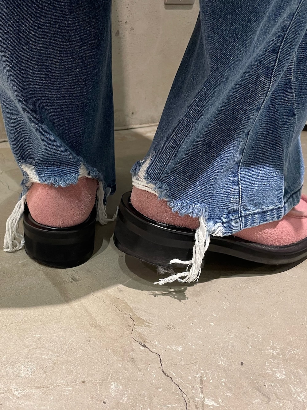 グレー系のステンカラーコート、ピンク系のカーディガン/ボレロ、ブルー系のデニムパンツを着用したメンズの秋コーディネートの4枚目の写真