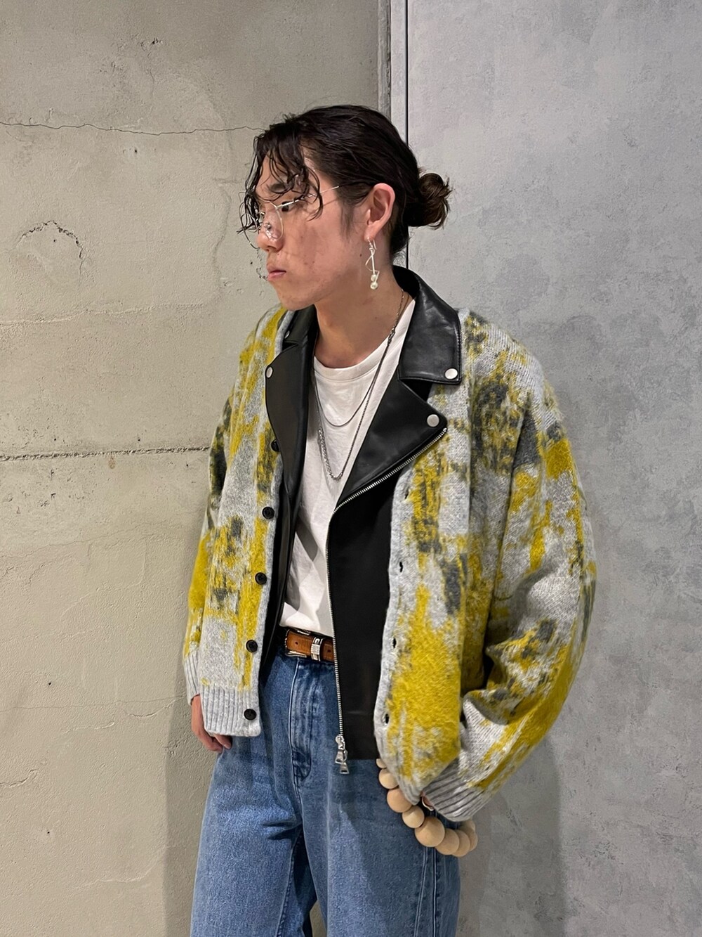 イエロー系のカーディガン/ボレロ、ブラック系のライダースジャケット、ブルー系のデニムパンツを着用したメンズの秋コーディネートの2枚目の写真