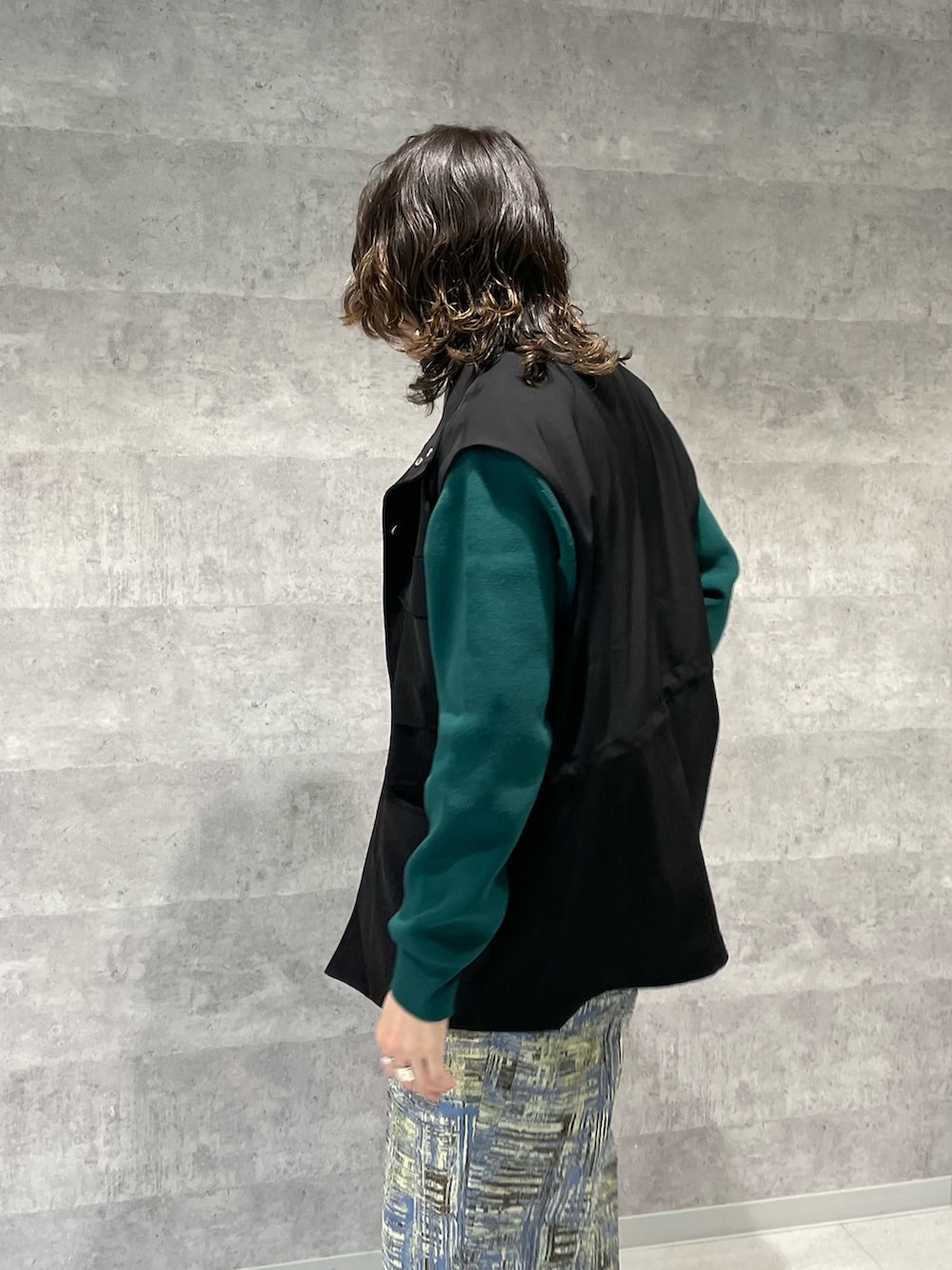 ブラック系のベスト、グリーン系のカーディガン/ボレロ、ブルー系のその他パンツを着用したメンズの春コーディネートの3枚目の写真