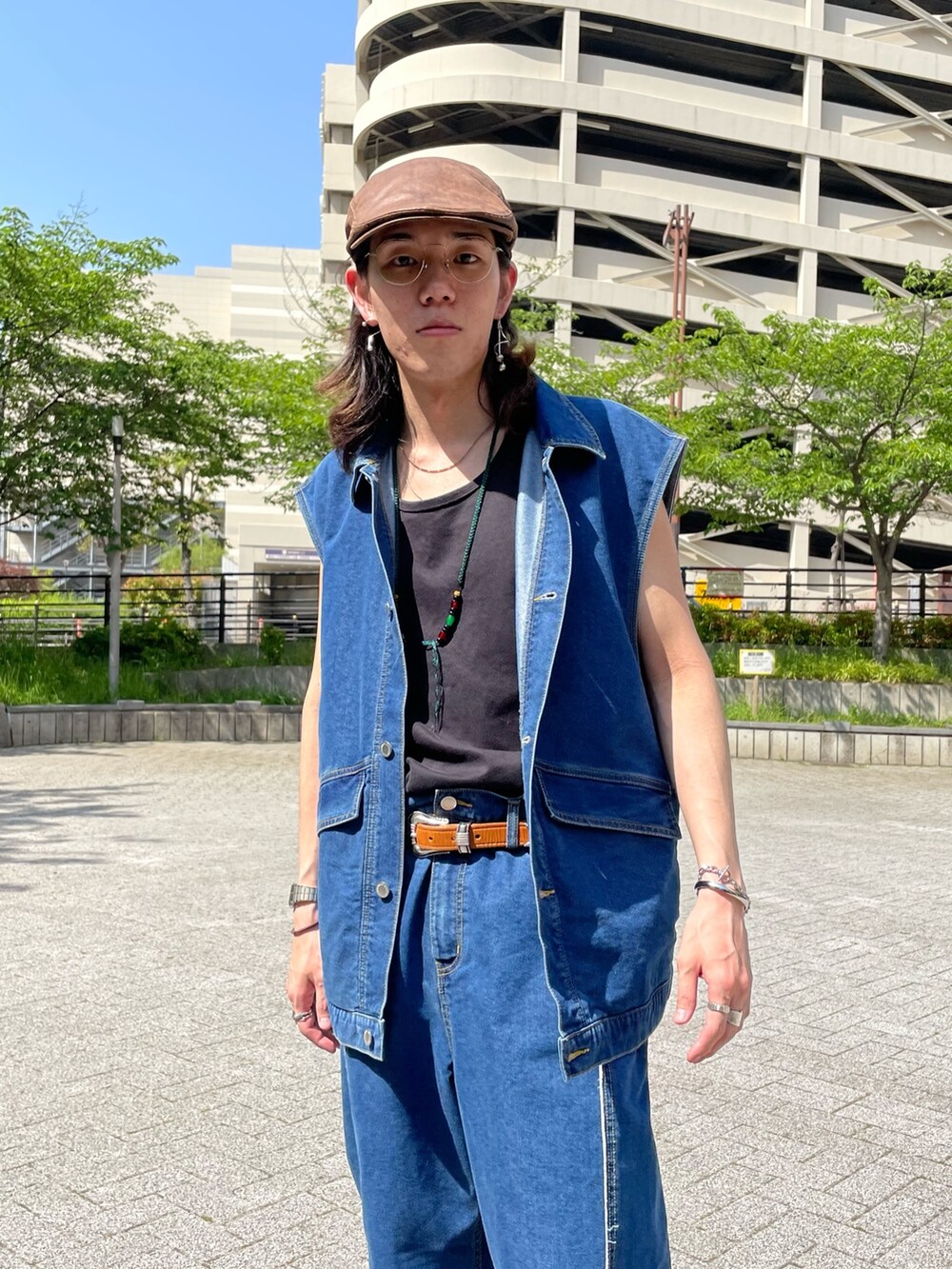 ブルー系のベスト、ブラック系のタンクトップ、ブルー系のデニムパンツを着用したメンズの春コーディネートの3枚目の写真