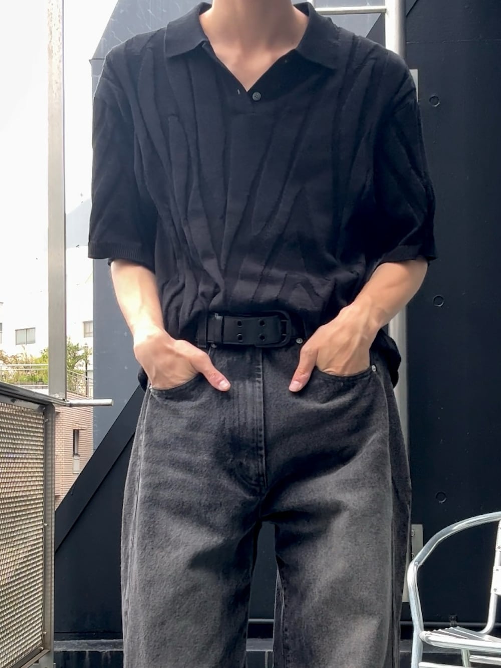 ブラック系のニット/セーター、ブラック系のスニーカー、ブラック系のデニムパンツを着用したメンズの夏コーディネートの2枚目の写真