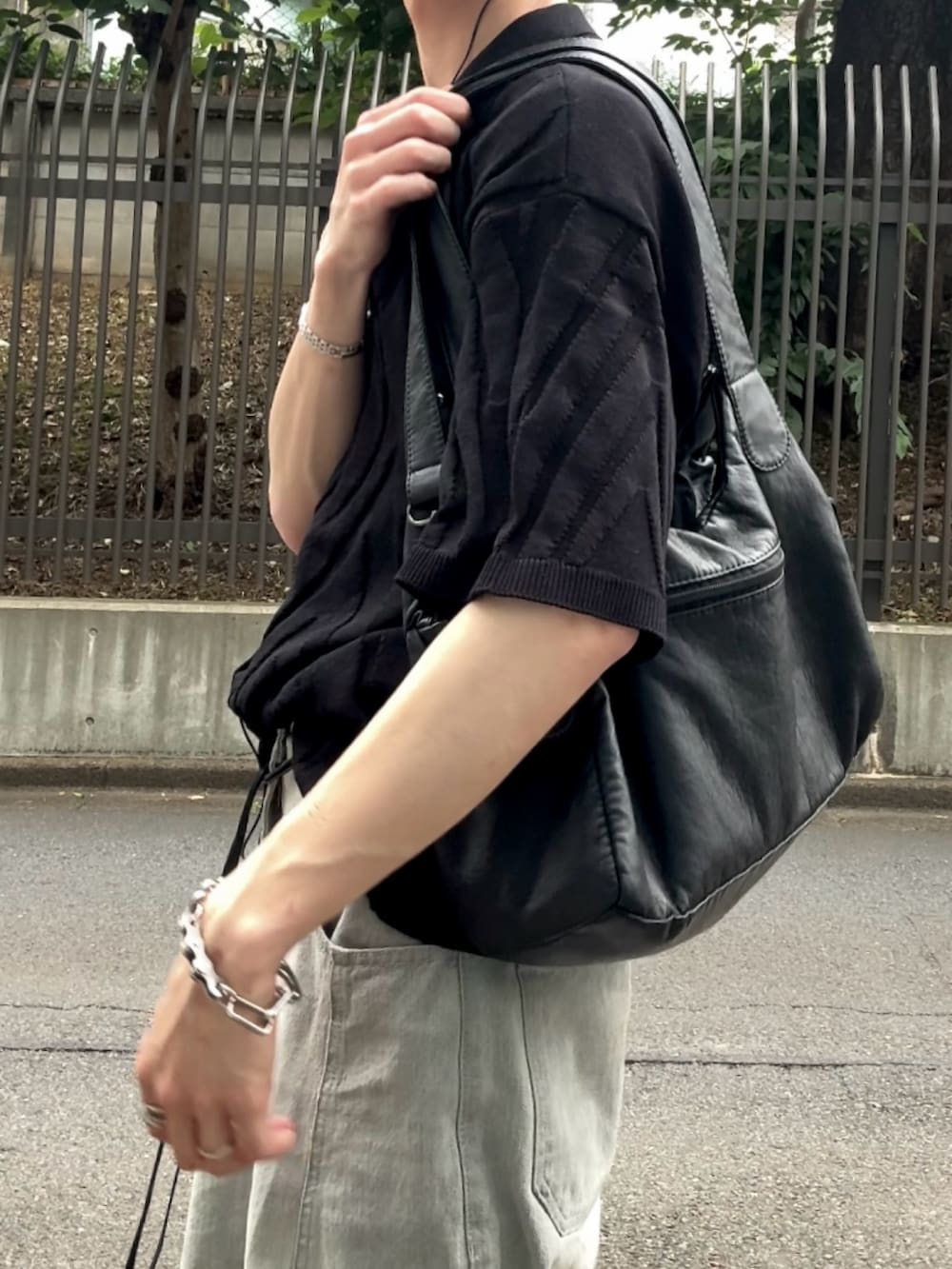 グレー系のデニムパンツ、ブラック系のスニーカー、ブラック系のニット/セーターを着用したメンズの夏コーディネートの3枚目の写真