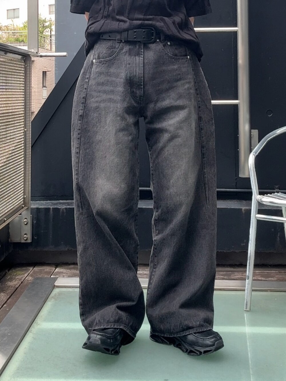 ブラック系のニット/セーター、ブラック系のスニーカー、ブラック系のデニムパンツを着用したメンズの夏コーディネートの3枚目の写真