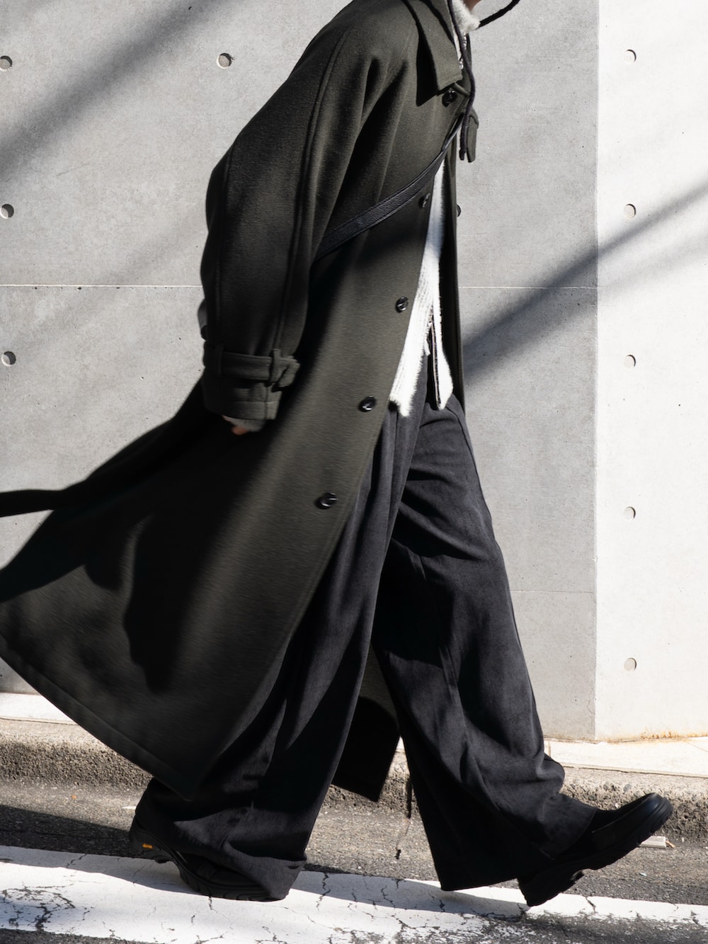 グリーン系のステンカラーコート、ブラック系のその他パンツ、ブラック系のスニーカーを着用したメンズの秋コーディネートの2枚目の写真