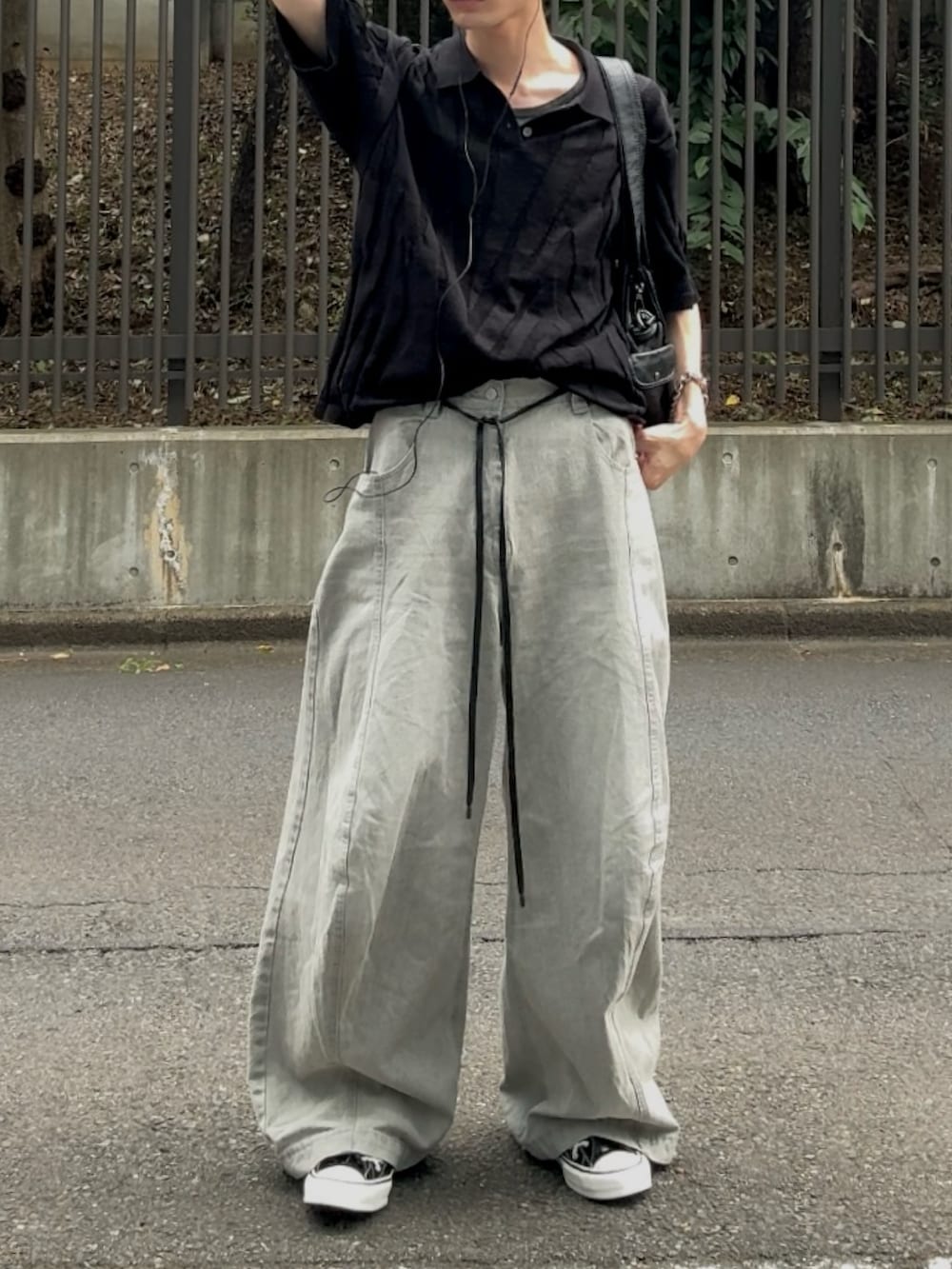 グレー系のデニムパンツ、ブラック系のスニーカー、ブラック系のニット/セーターを着用したメンズの夏コーディネートの2枚目の写真