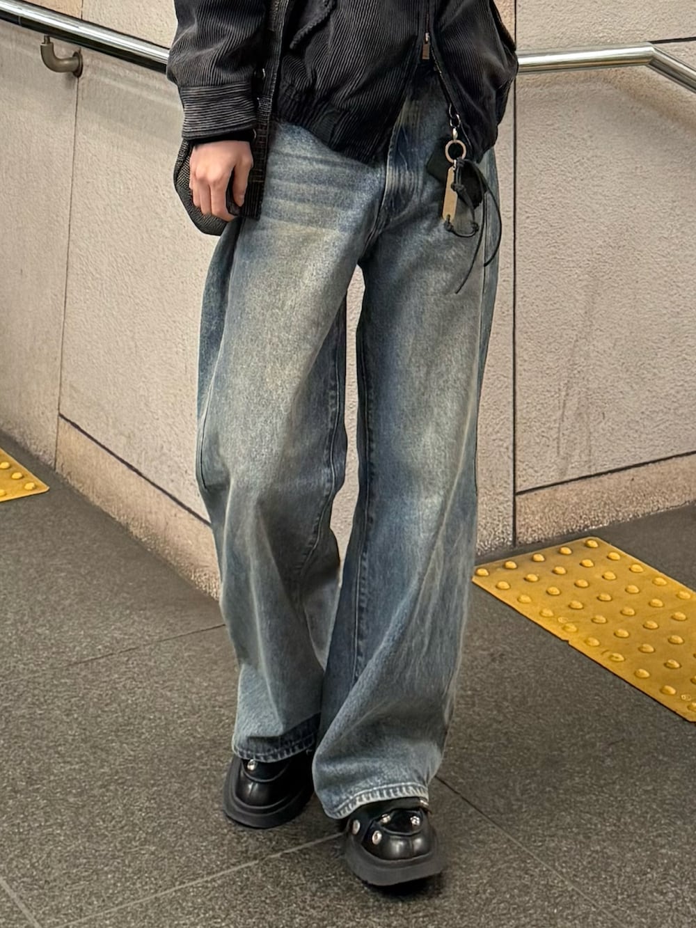 ブルー系のデニムパンツ、ブラック系のドレスシューズ、ブラック系のブルゾンを着用したメンズの春コーディネートの2枚目の写真