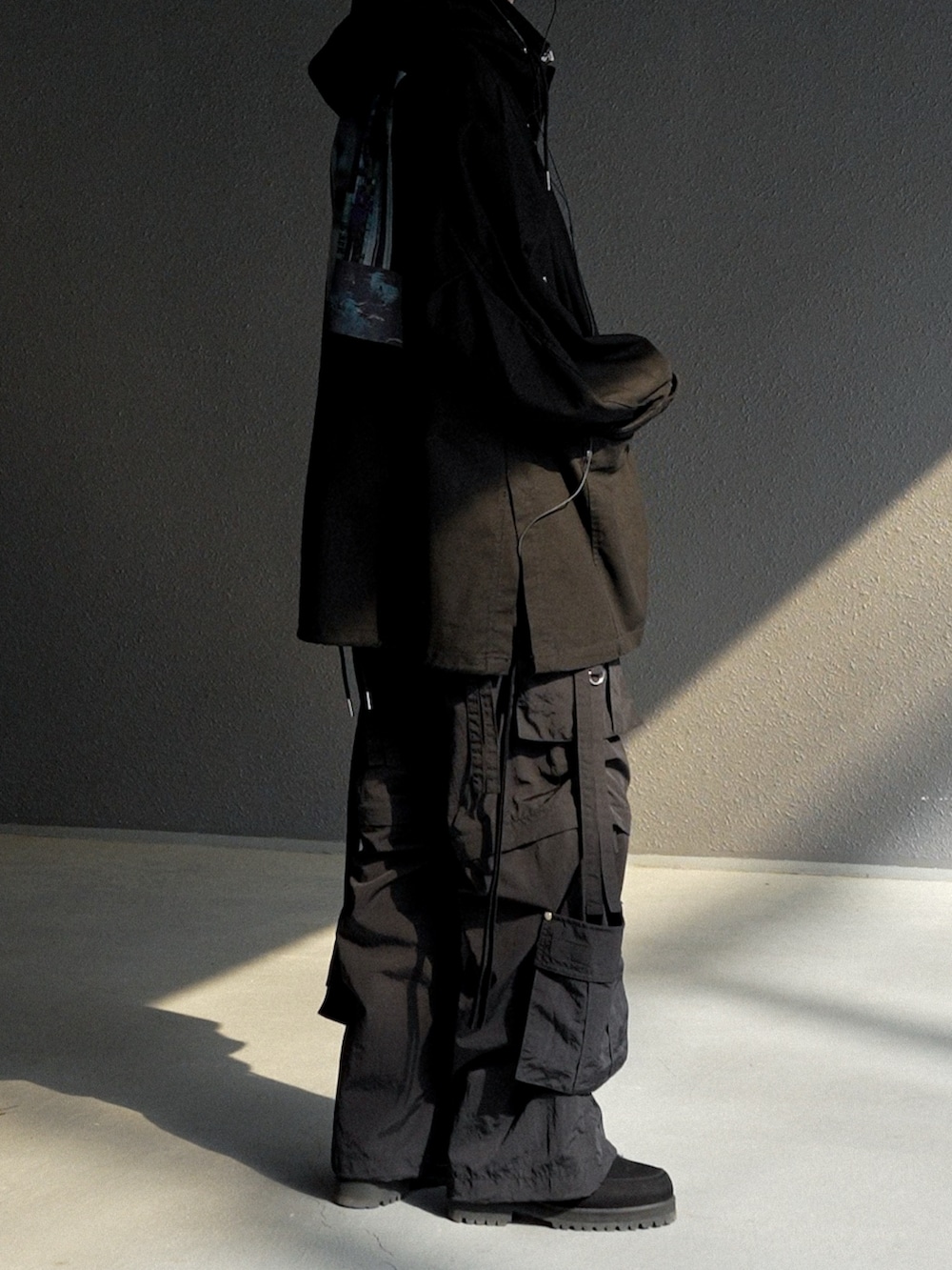 ブラック系のパーカー、ブラック系のその他パンツ、ブラック系のブーツを着用したメンズの春コーディネートの2枚目の写真