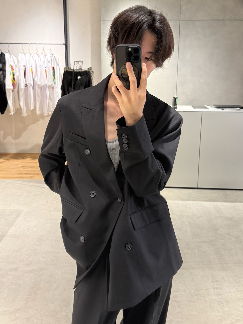 グレー系のタンクトップ、ブラック系のテーラードジャケット、ブラック系のスラックスを着用したメンズの秋コーディネートの3枚目の写真