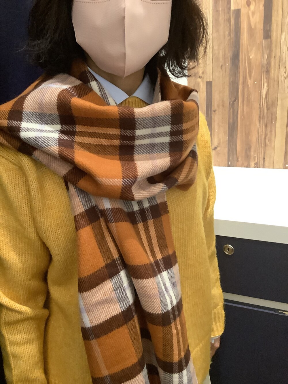 ブルー系のビジネスシャツ、イエロー系のニット/セーター、オレンジ系のストール/ショールを着用したレディースの冬コーディネートの2枚目の写真