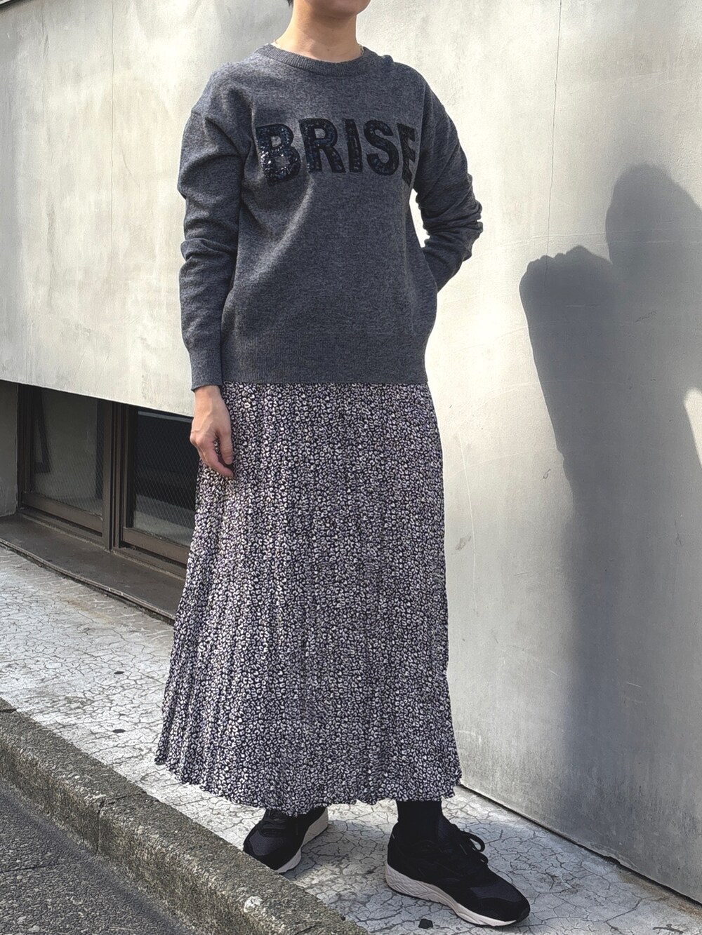 ベージュ系のムートンコート、グレー系のニット/セーター、ブラック系のスカートを着用したレディースの冬コーディネートの2枚目の写真