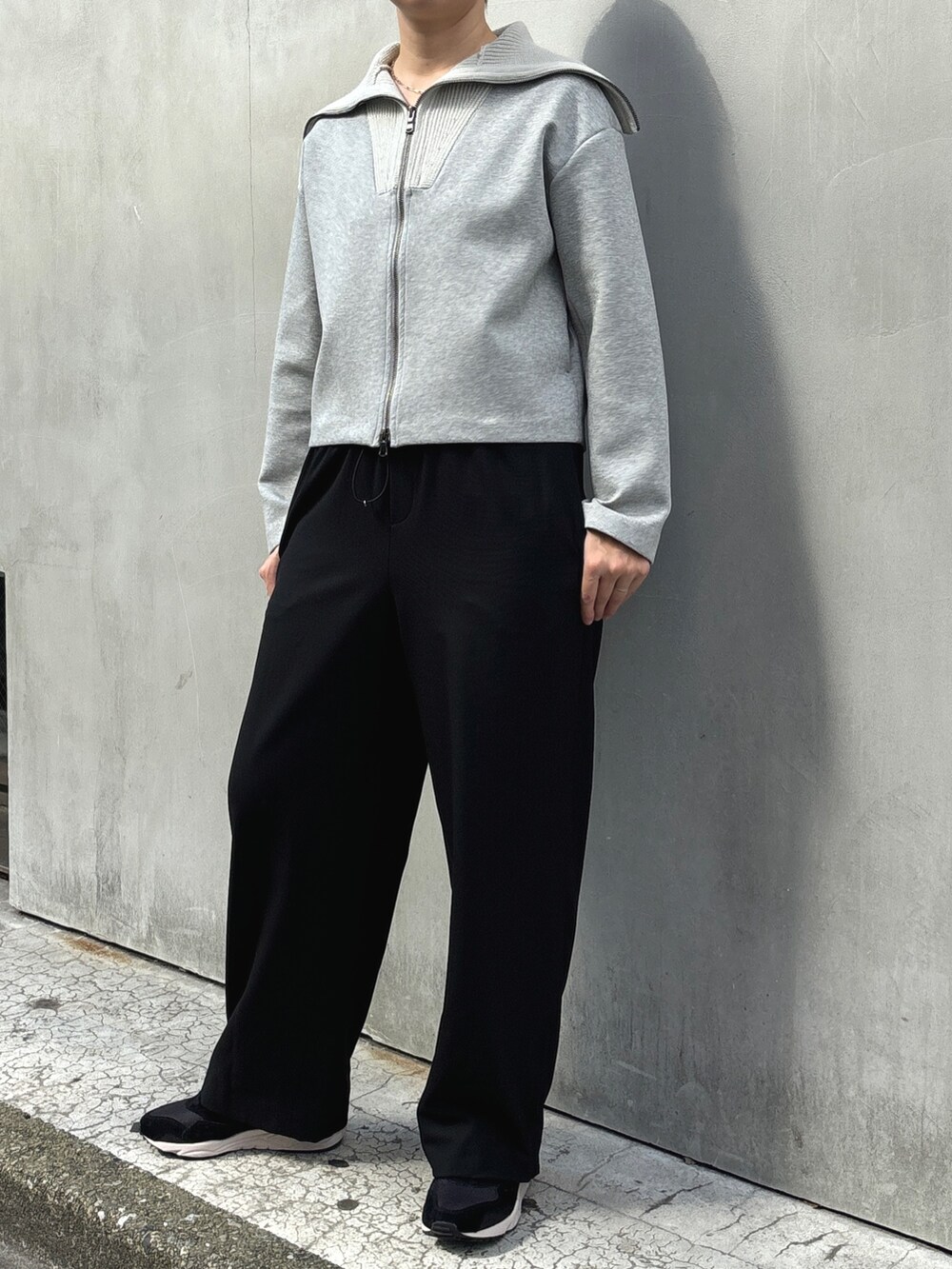 ブルー系のノーカラーコート、ブラック系のその他パンツ、グレー系のTシャツ/カットソーを着用したレディースの冬コーディネートの2枚目の写真